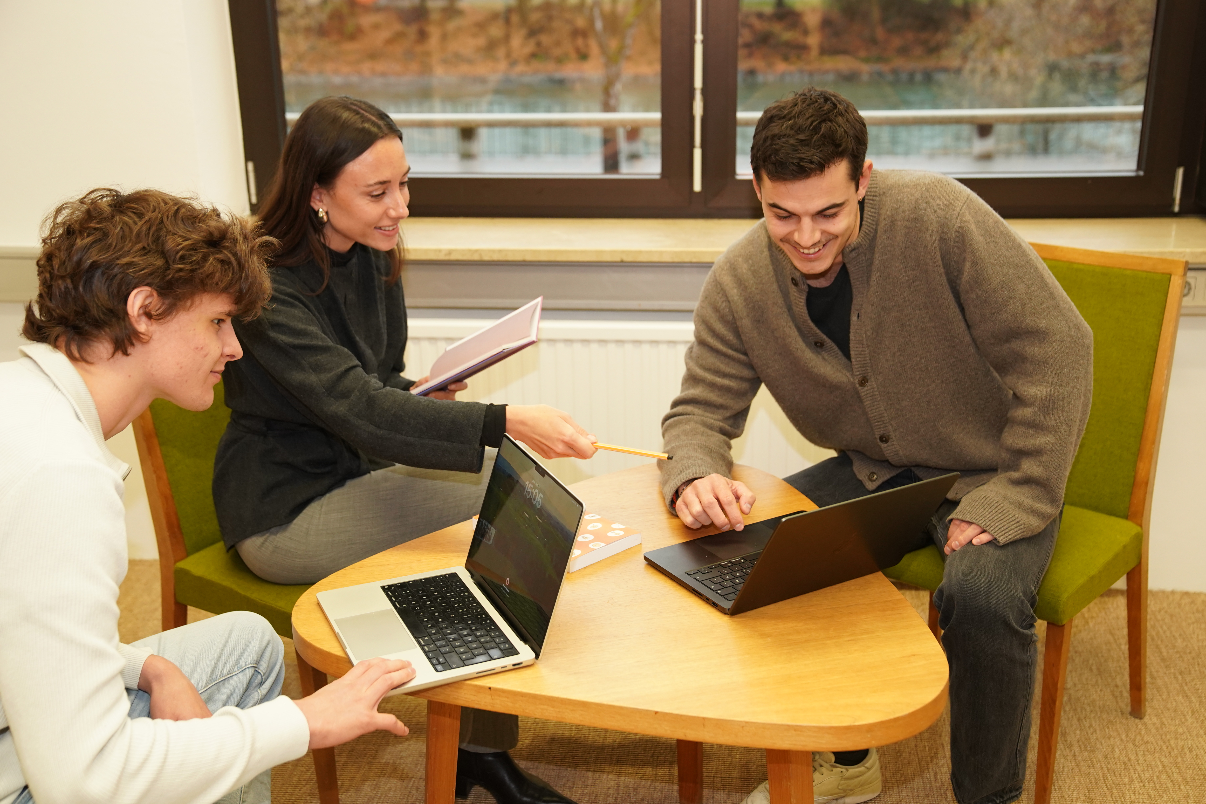 3 Personen am Tisch diskutieren bei einem Meeting 