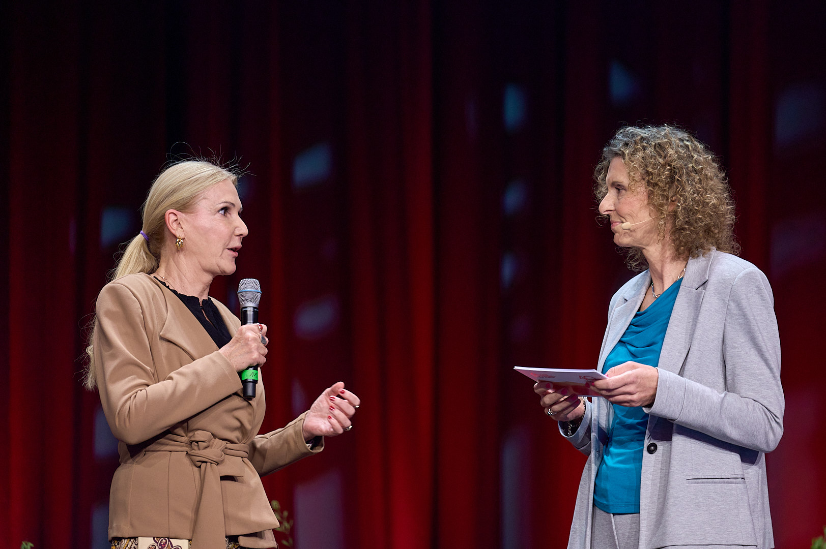Nahaufnahme von zwei Personen, die sich unterhalten. Eine davon hält ein Mikrofon in der Hand