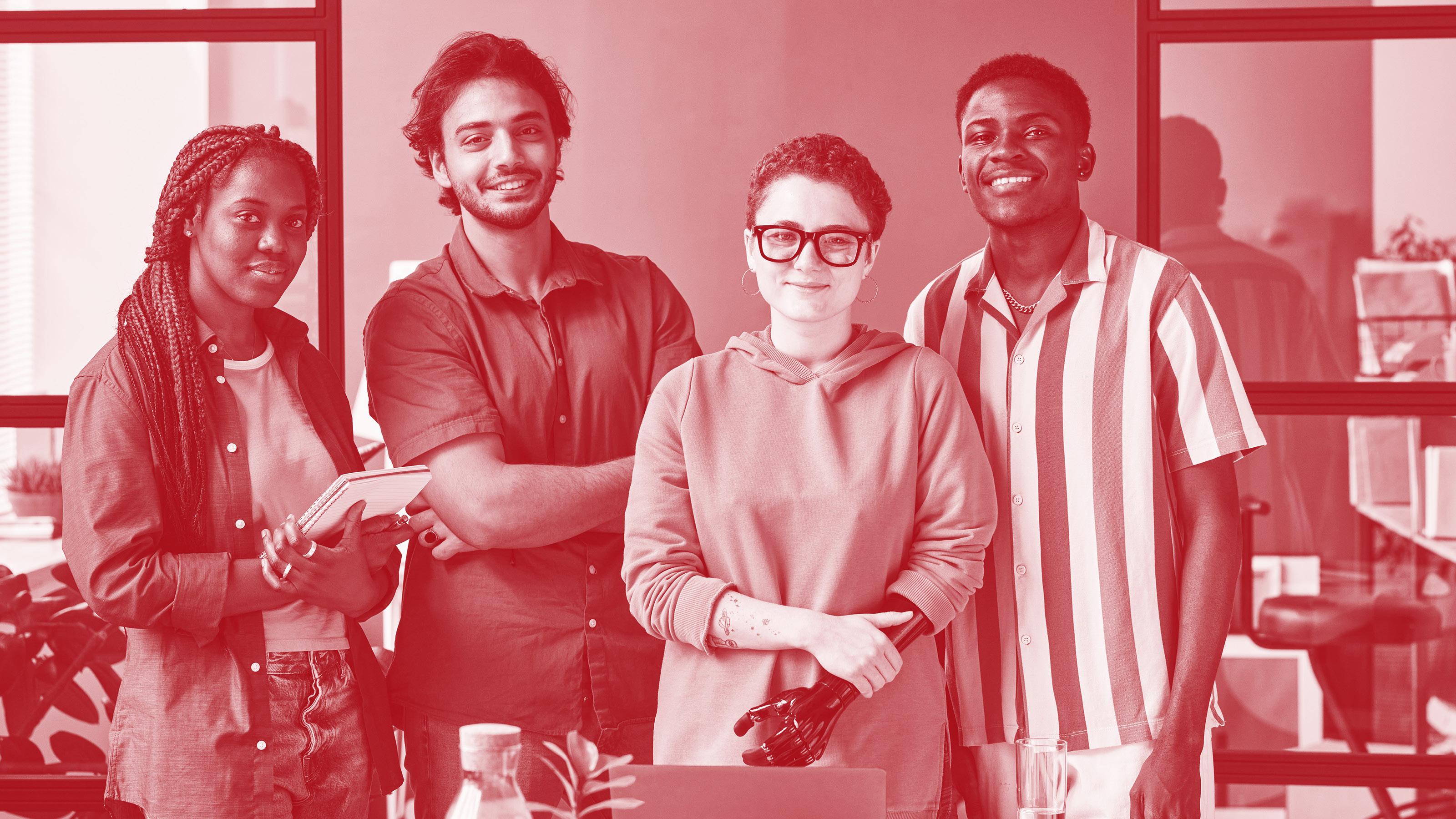 Junges Kreativ-Designteam bestehend aus zwei Frauen und zwei M&auml;nnern posiert vor einem Laptop