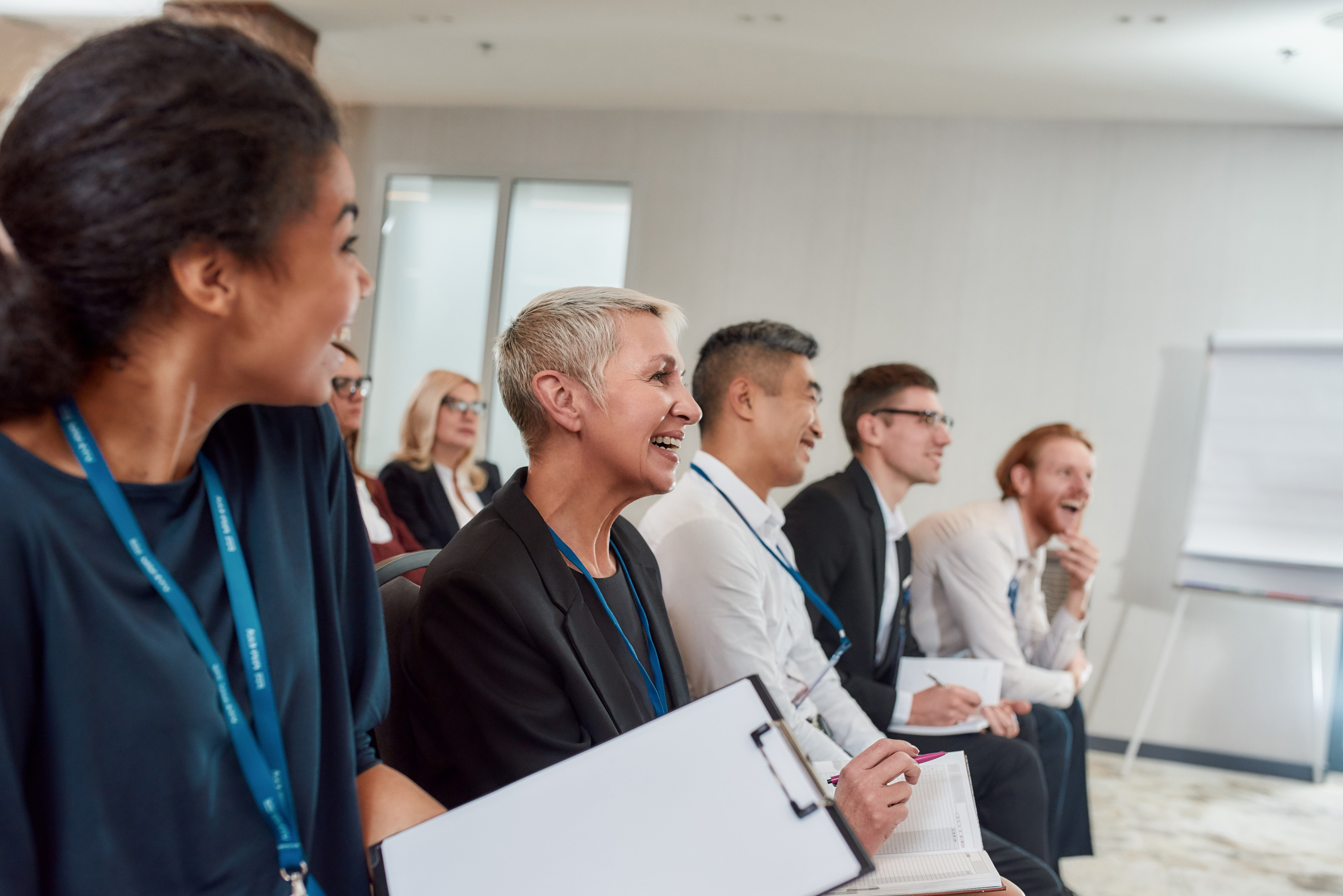Personen im Publikum eines Konferenzraumes blicken freudig nach vorne