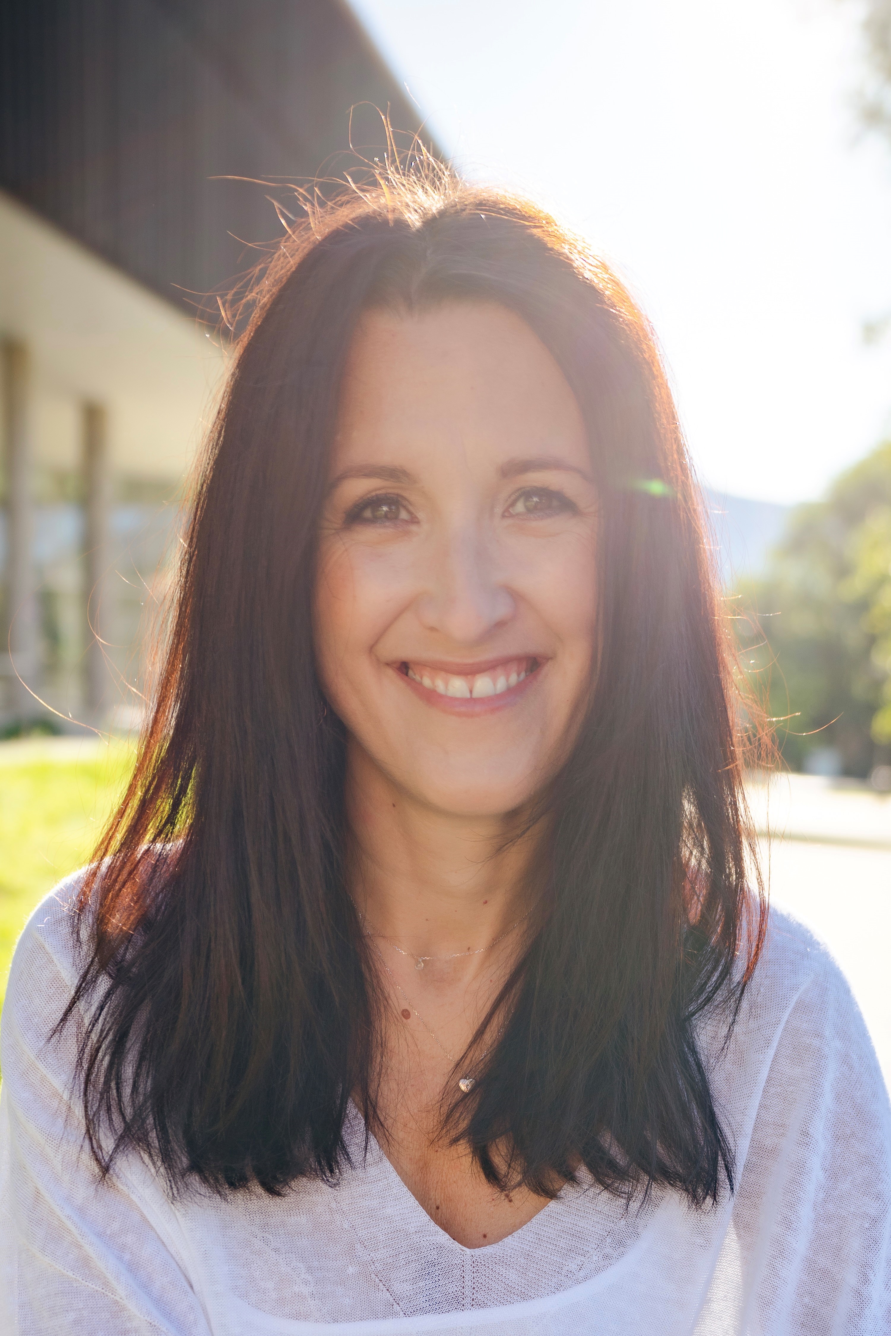 Portraitfoto einer Person mit dunklem Haar im Freien bei Sonnenlicht