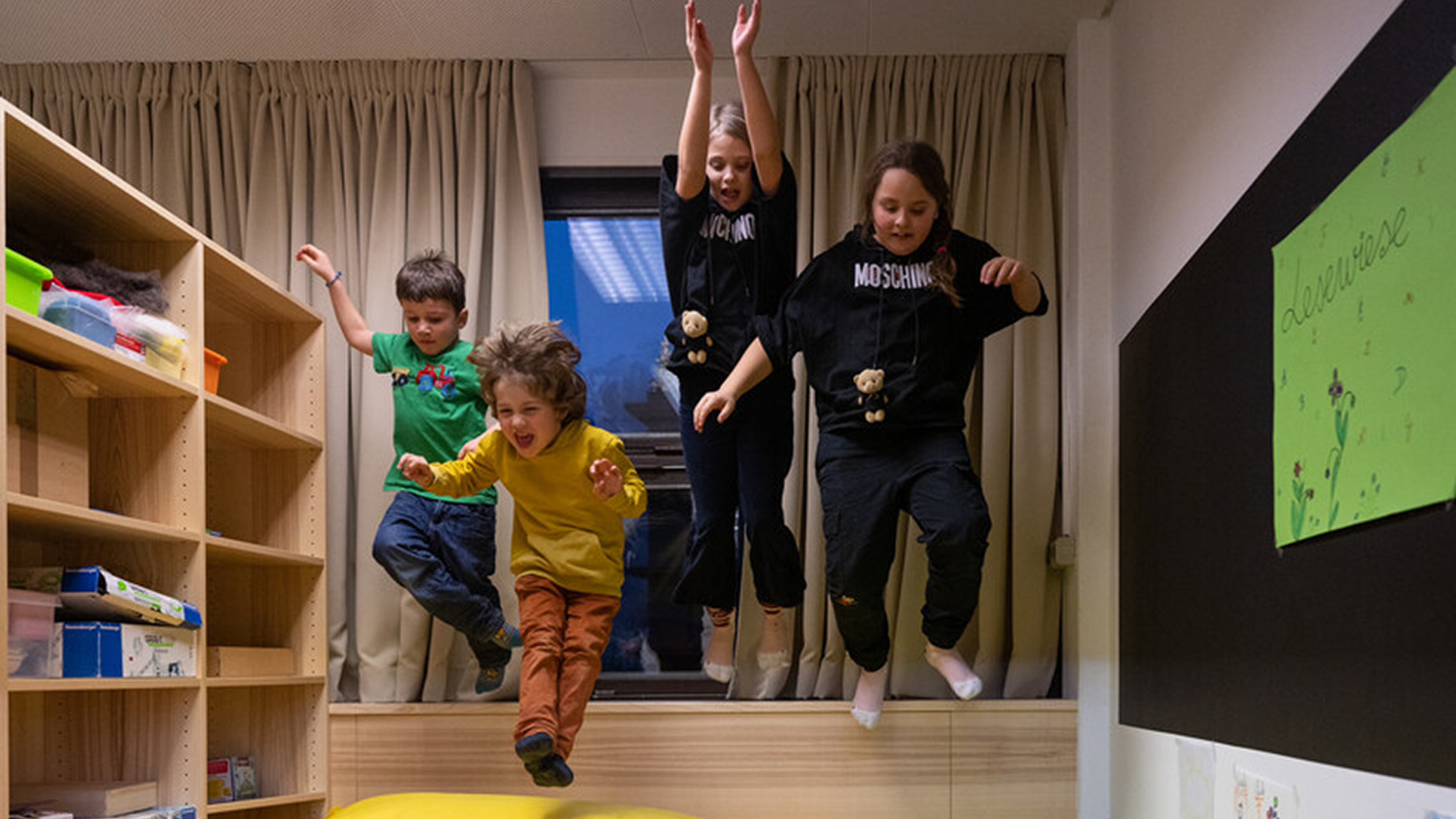 Vier Kinder in einem Zimmer hüpfen in der Luft