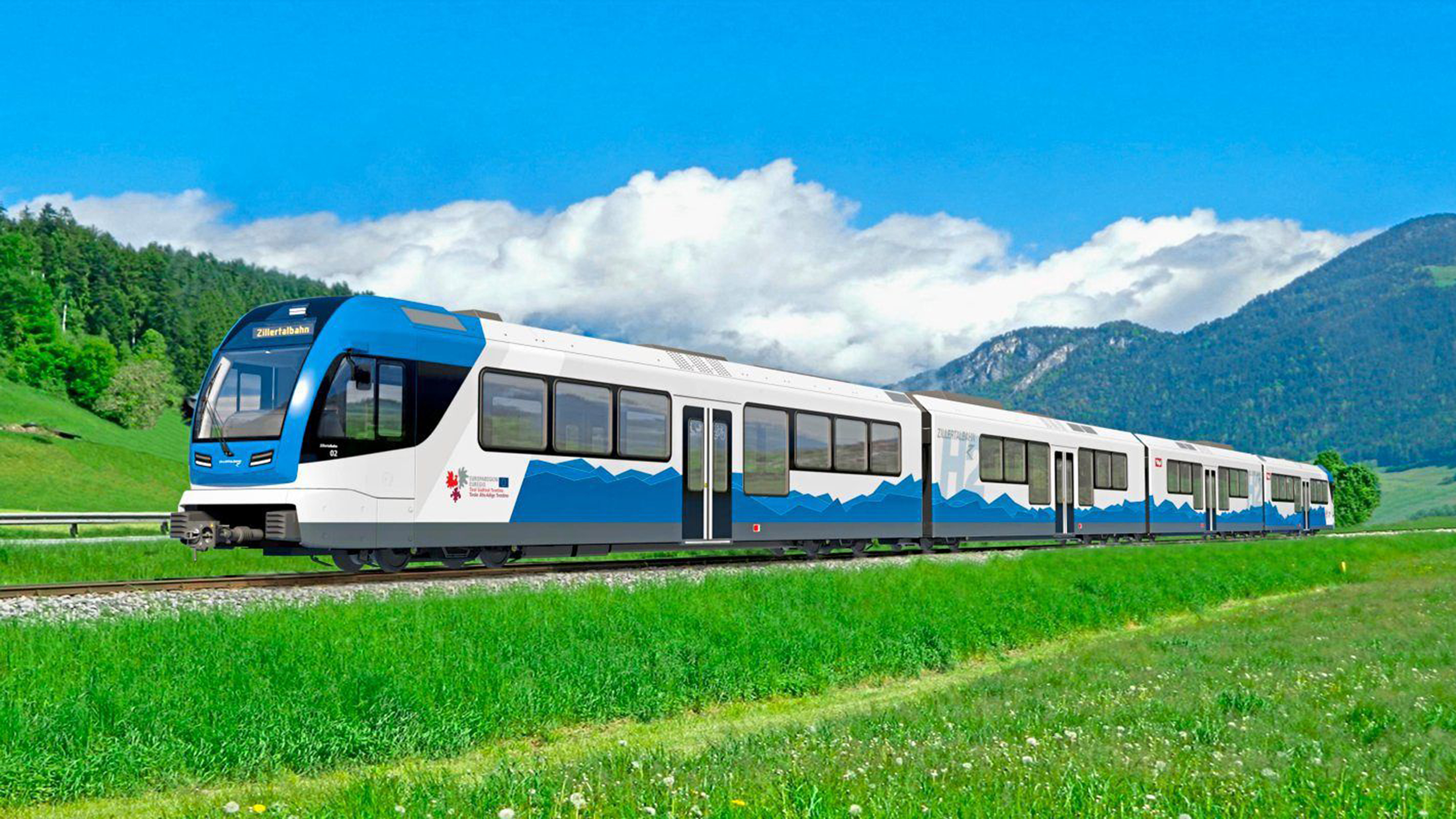 Fahrender Zug mit der Aufschrift "Zillertalbahn" und grüne Wiese