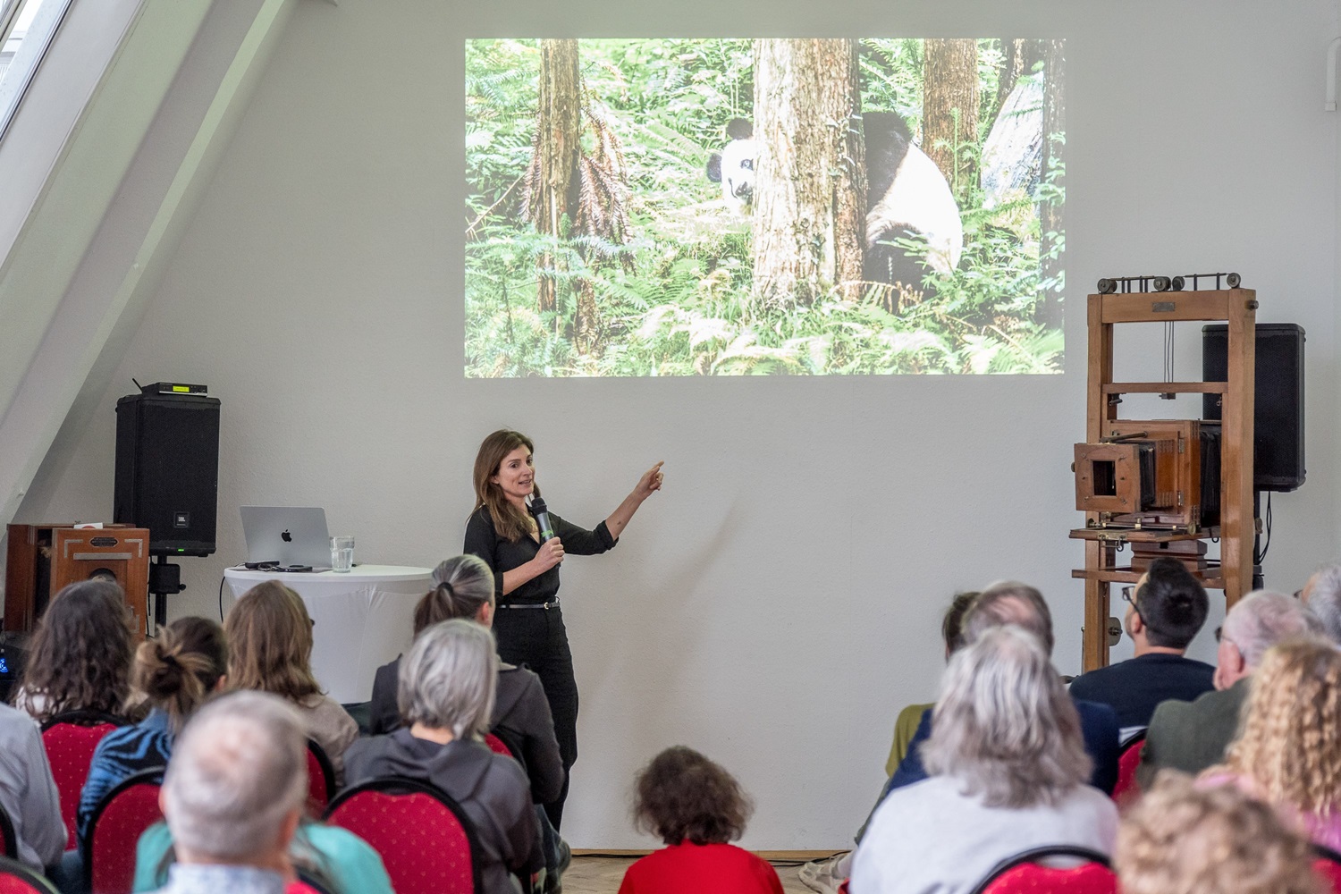 stehende Frau mit Mikro h&auml;lt Vortrag