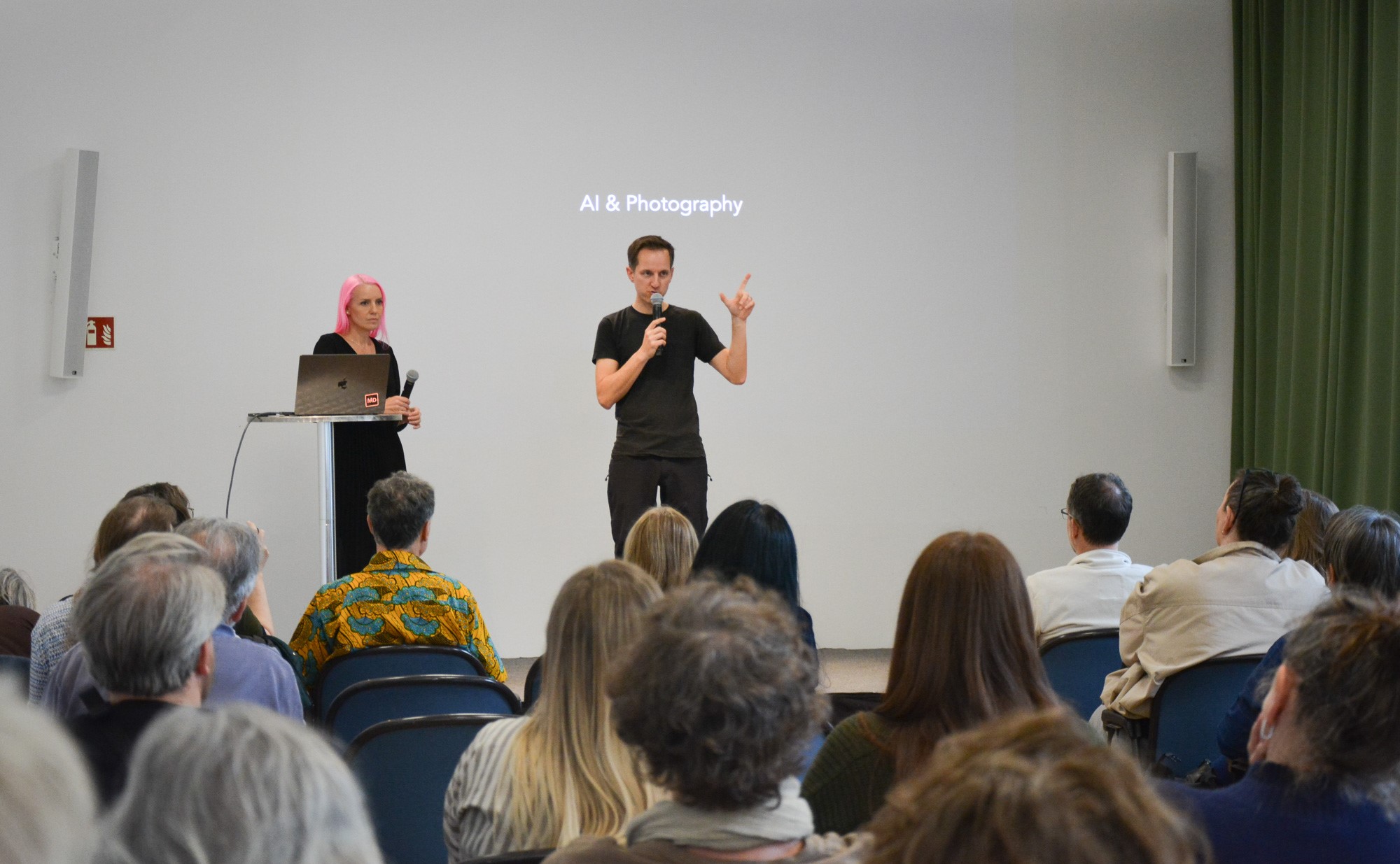 Vortrag zu &bdquo;AI & Photography&ldquo; vor Publikum mit zwei Personen auf einer B&uuml;hne