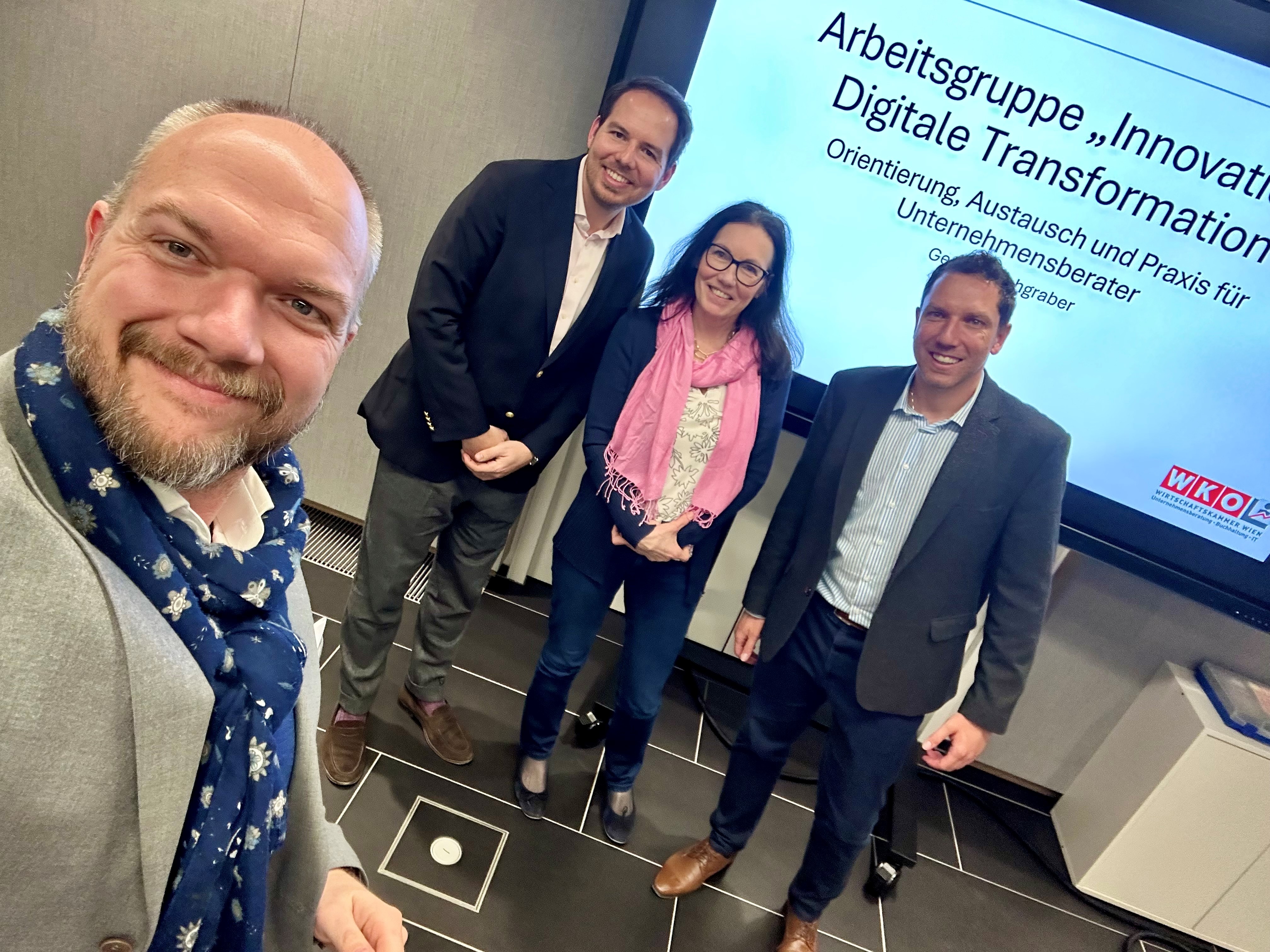 eine Frau und drei M&auml;nner stehen vor Pr&auml;sentation