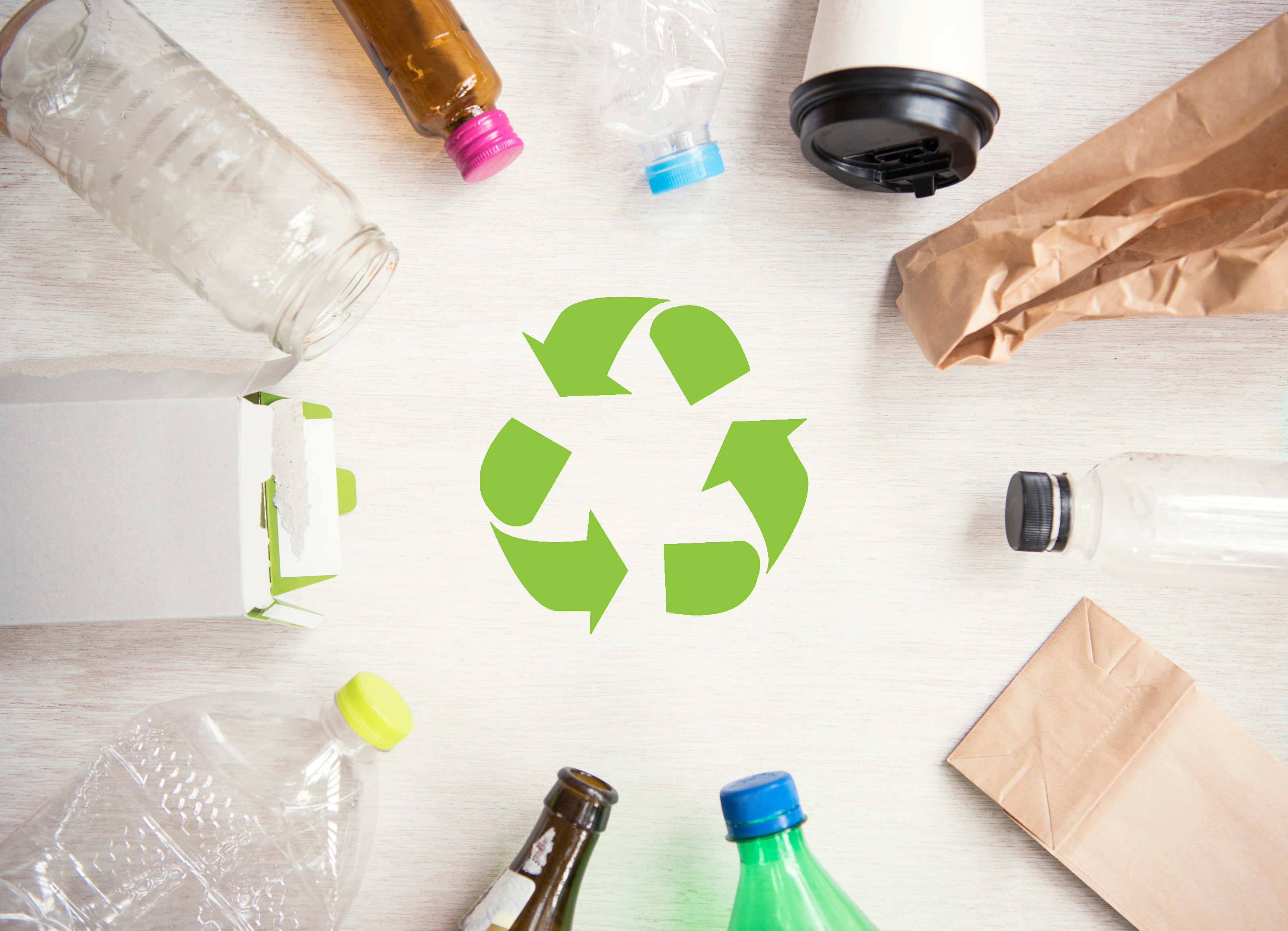 Eine grafische Darstellung eines gr&uuml;nen Recycling-Symbols: Drei Pfeile im Kreis laufend. Drumherum liegen unterschiedliche recycelbare Verpackungen wie Flaschen, T&uuml;ten und Becher.