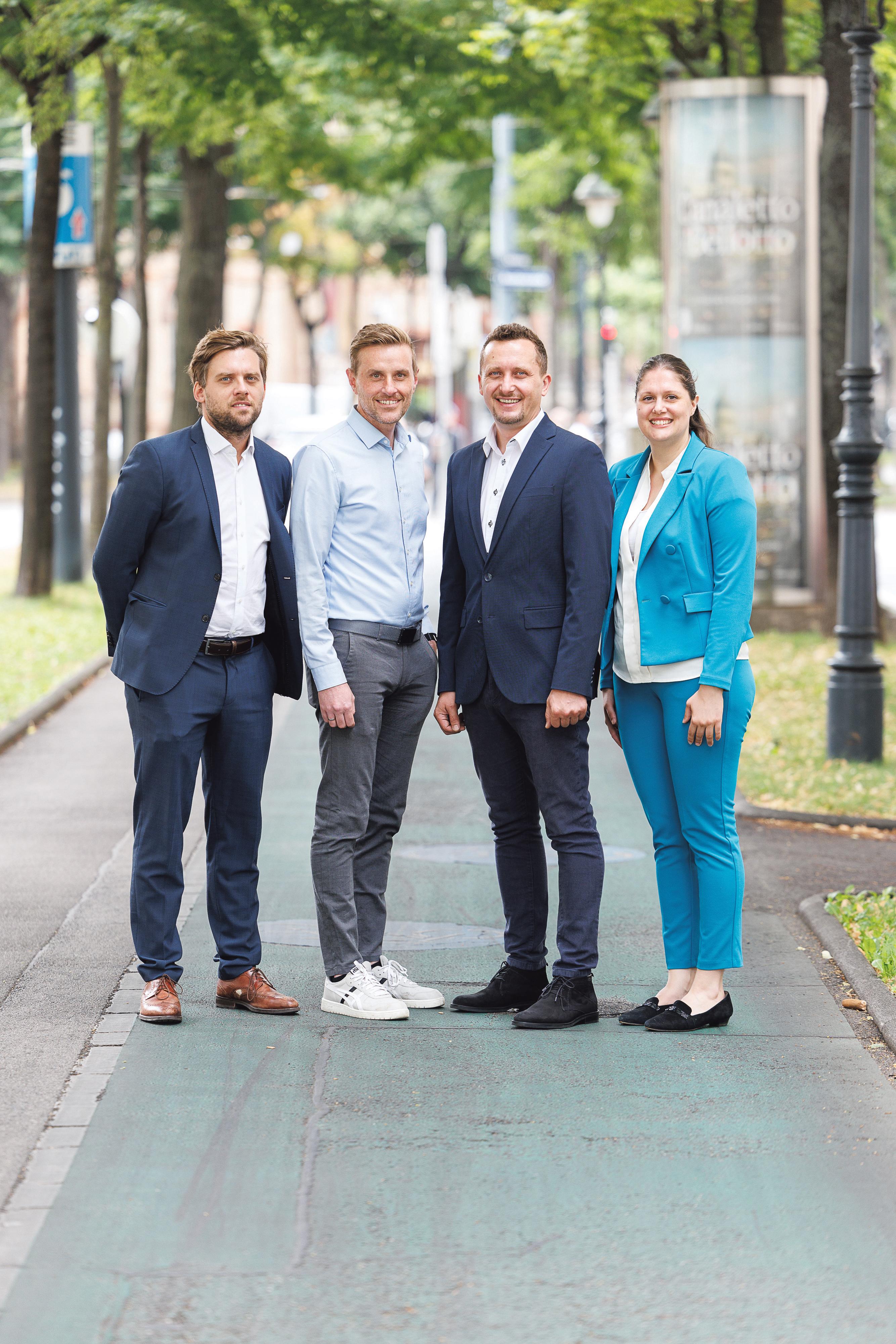 3 M&auml;nner und 1 Frau im Businessoutfit auf einem begr&uuml;nten Platz in Wien