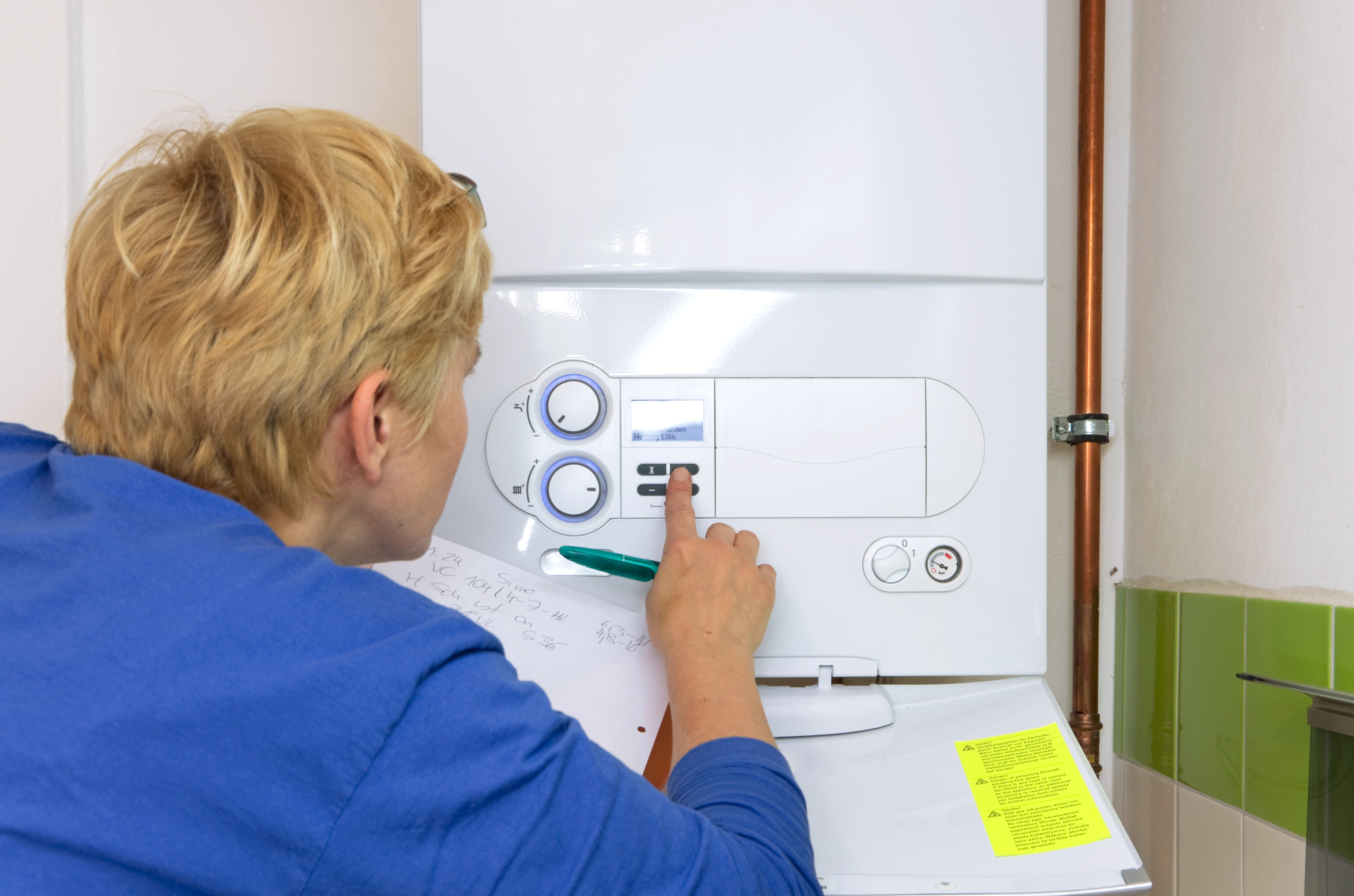 Person mit hellen kurzen Haaren und Brille führt eine Gasthermenwartung durch