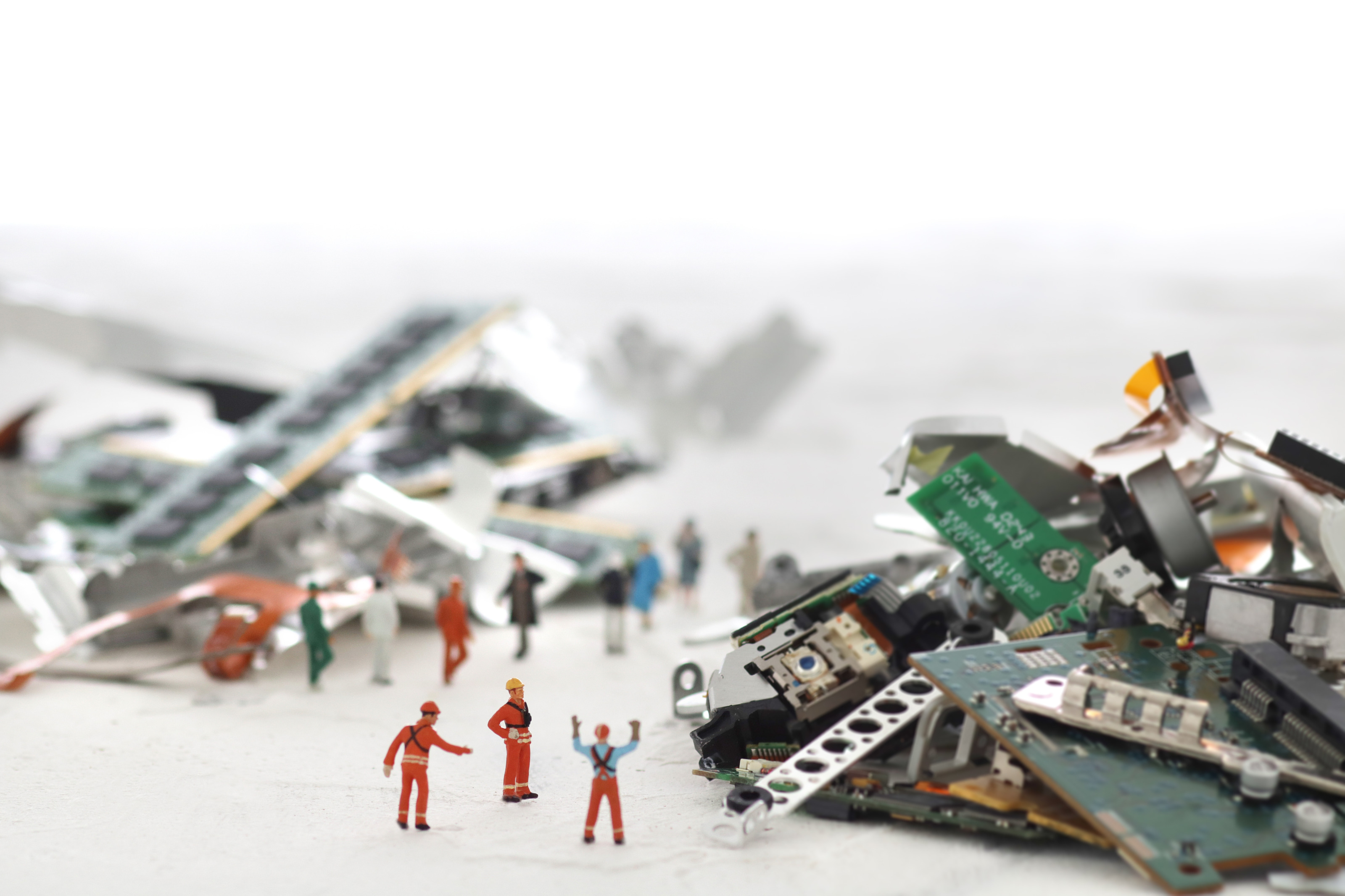 Spielfiguren stehen neben Haufen voller geschredderter Computerplatinen