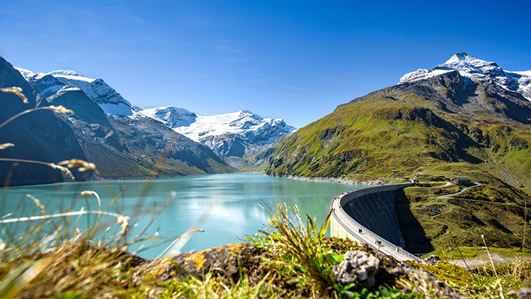 Stausee mit beschneitem Gebirgszug im Hintergrund