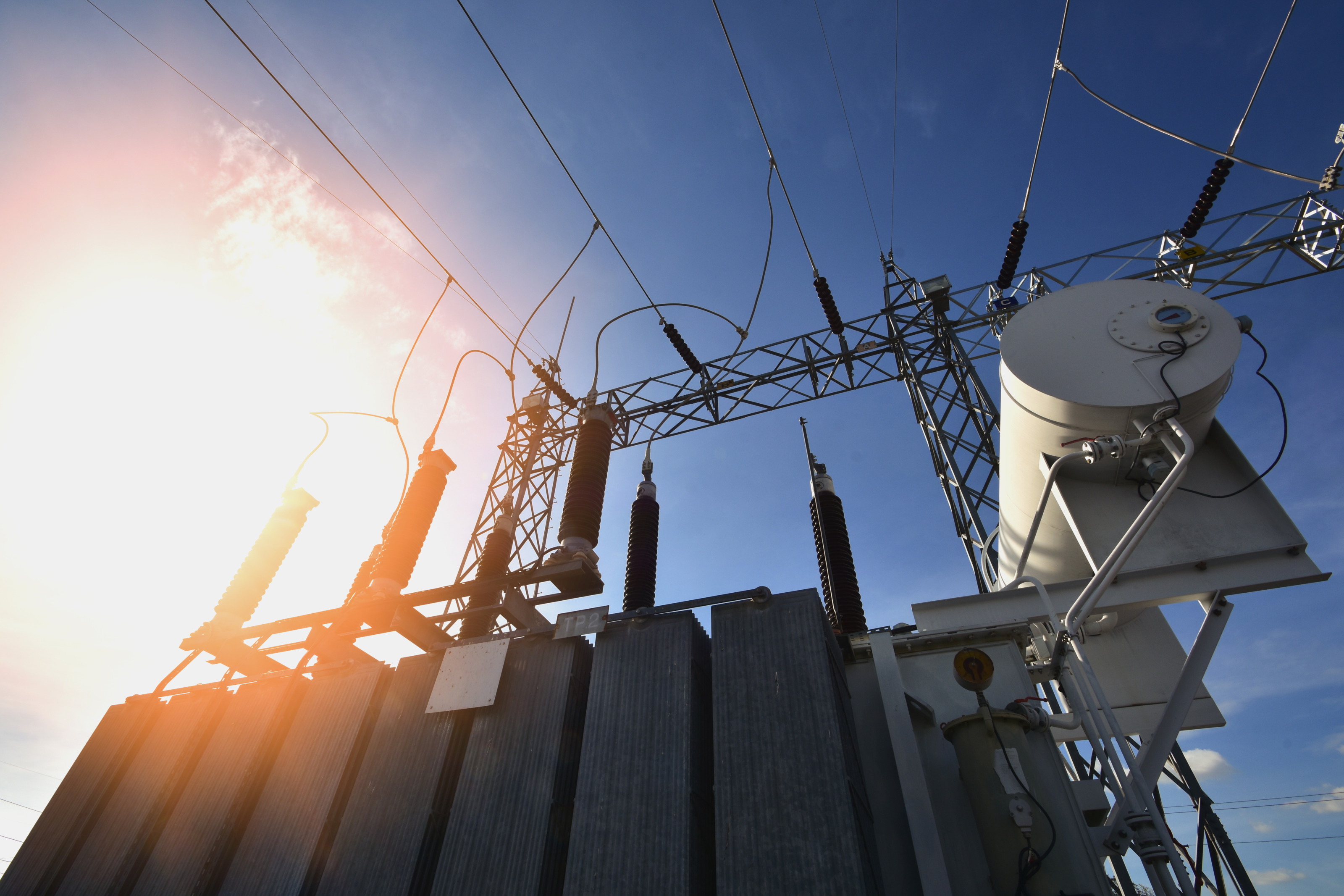Ansicht Speicher eines Stromkraftwerkes nach oben mit Stromleitungen verbunden unter blauem Himmel mit Sonnenlicht